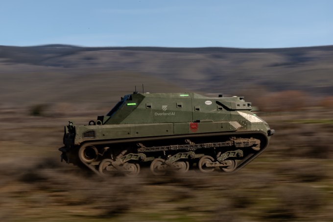 Imagem da lateral de um tanque dirigindo rápido em terreno off-road