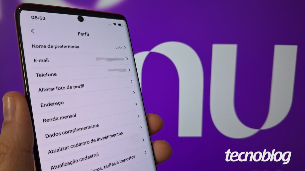 Uma mão segura um celular com o aplicativo do Nubank aberto no menu Perfil