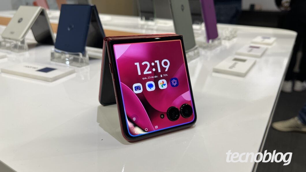 Razr 60 Ultra aberto no formato de tenda e apoiado sobre mesa. A tela externa tem um contorno colorido, indicando a ativação da Moto AI.