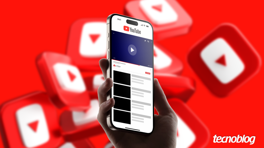 Imagem mostra uma m&atilde;o segurando um smartphone preto que exibe a interface do aplicativo YouTube. O logo do YouTube, um ret&acirc;ngulo branco com um tri&acirc;ngulo vermelho apontando para a direita, e a palavra "YouTube" em branco, aparecem na parte superior da tela do smartphone. O fundo da imagem &eacute; vermelho com v&aacute;rios logos do YouTube em diferentes tamanhos. Na parte inferior direita, o logotipo do "Tecnoblog" &eacute; vis&iacute;vel.
