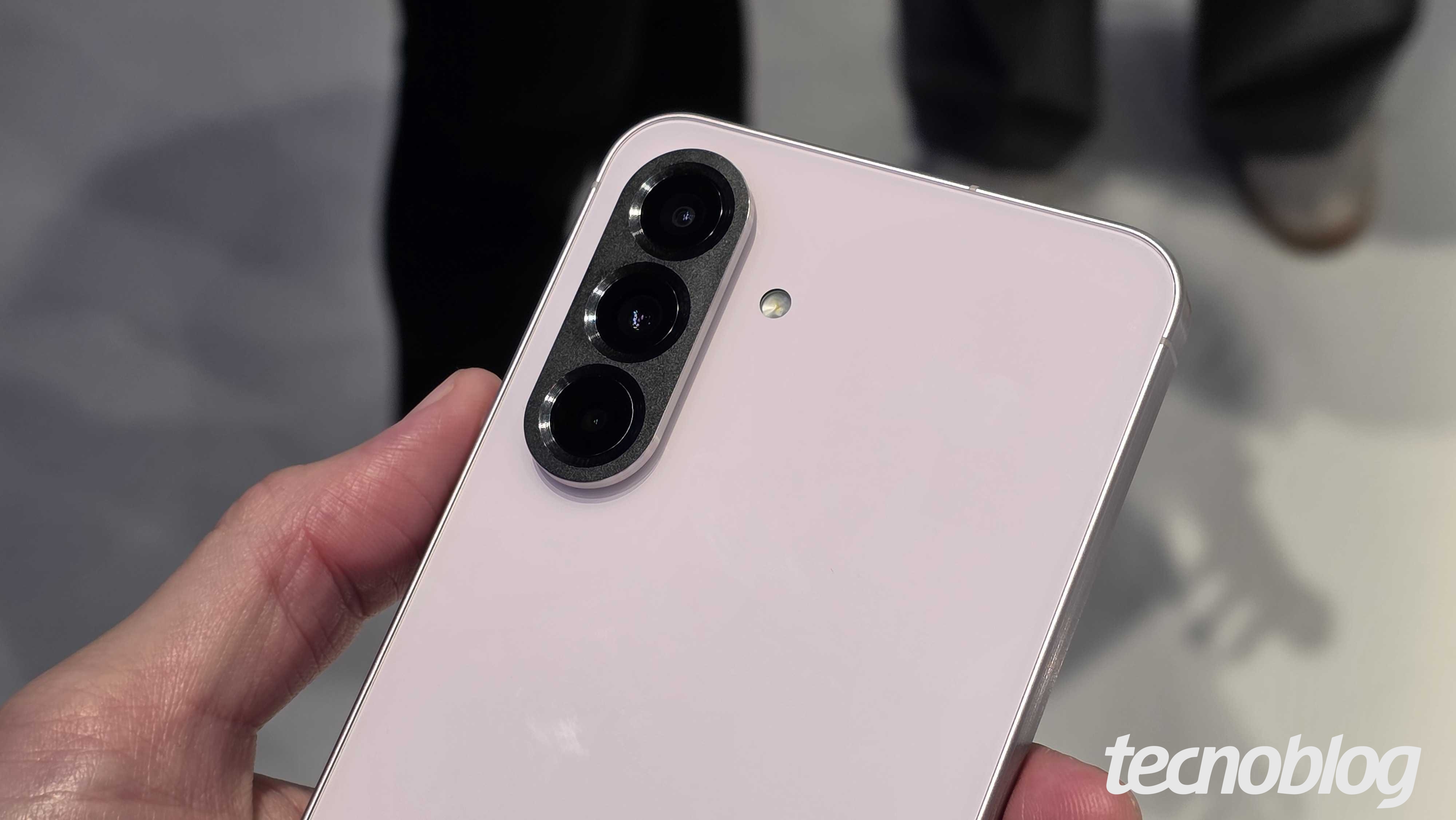 M&atilde;o segurando Galaxy A56 com a traseira virada pra cima (foto: Th&aacute;ssius Veloso/Tecnoblog)