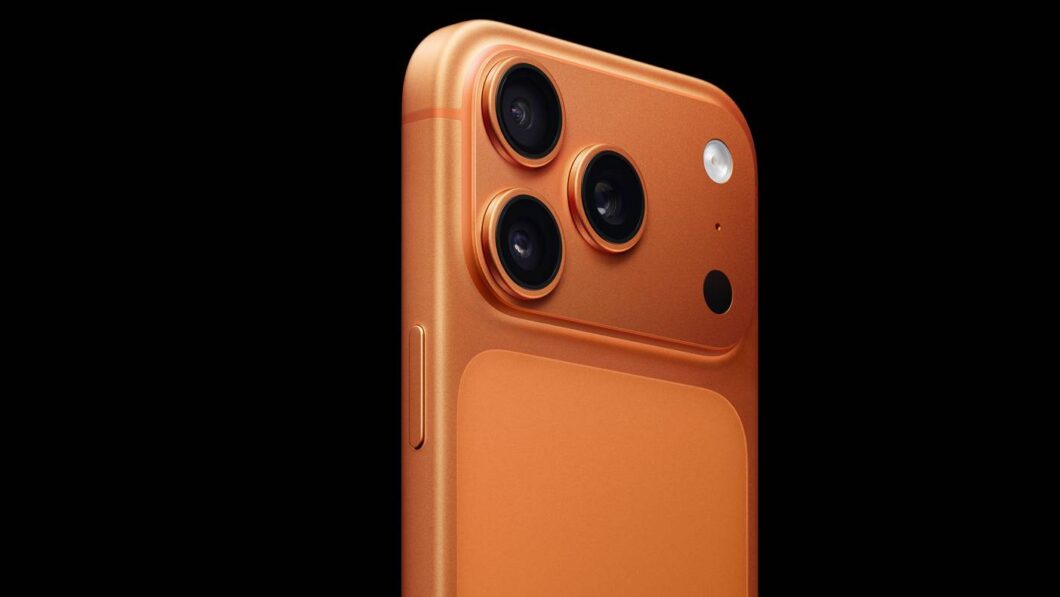 Foto de close-up em estúdio, em fundo preto, mostrando o canto superior traseiro de um iPhone 17 Pro na cor laranja-cobre fosca.