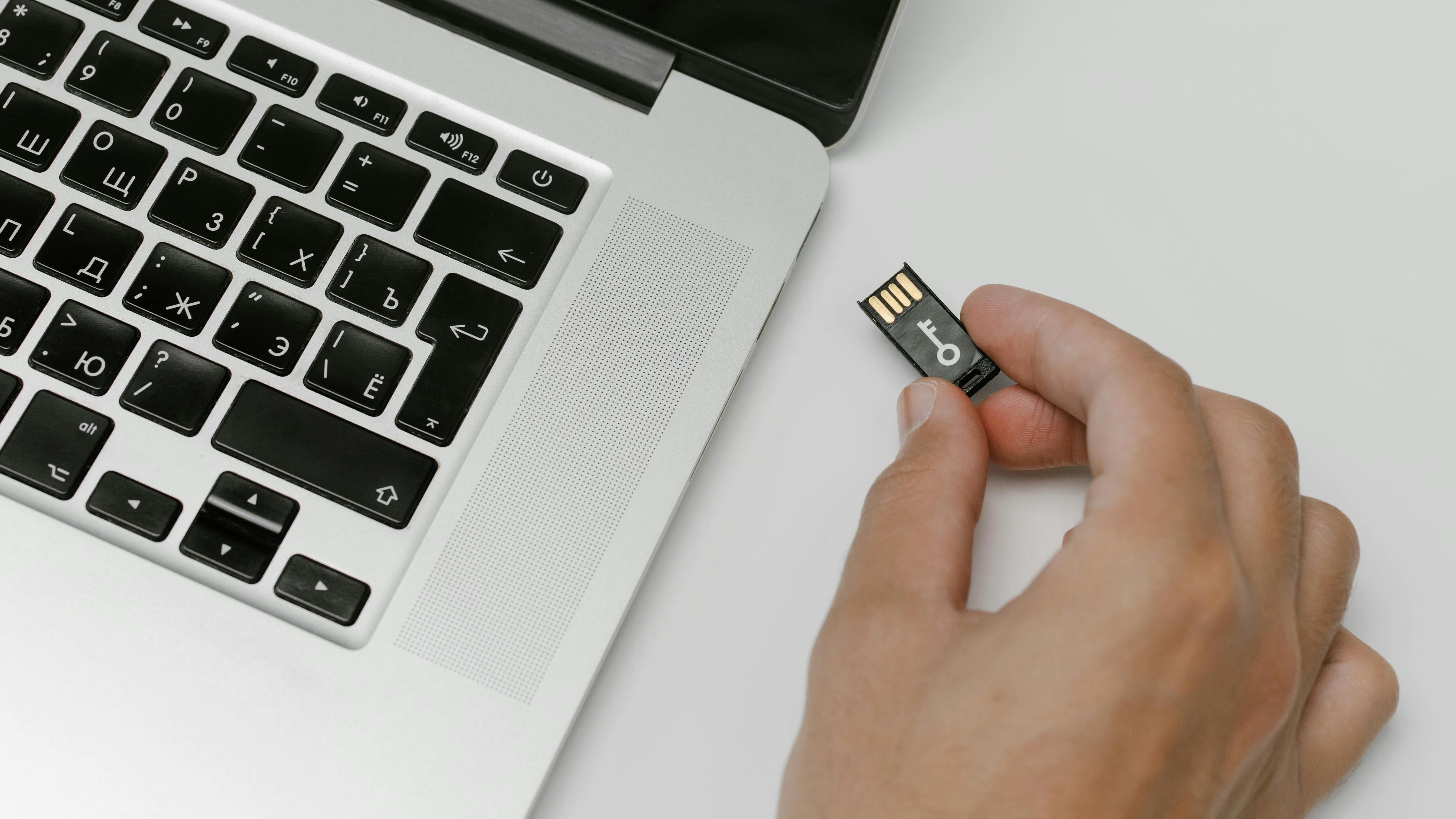 Foto de uma pessoa conectando um pendrive em um notebook branco