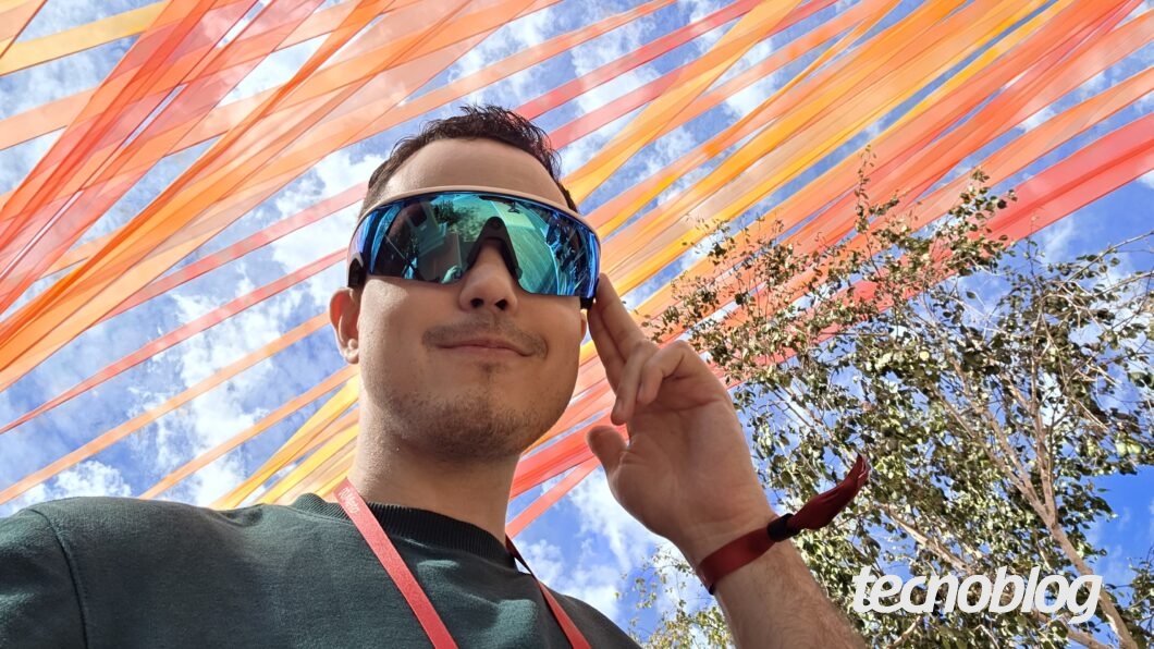 Imagem mostra uma pessoa com um óculos smart Oakley Meta Vanguard. Na parte inferior direita, o logotipo do "tecnoblog".