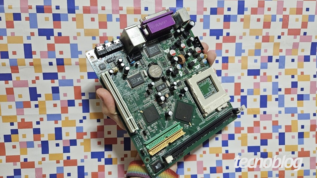 Mão segurando placa mãe sobre fundo abstrato