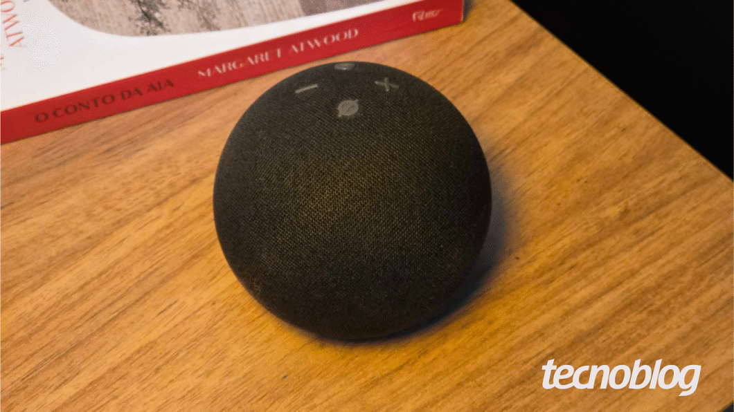 Amazon Echo Dot sobre uma mesa com um livro ao fundo