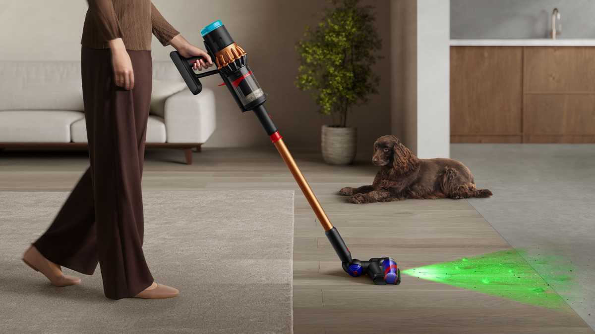 Someone using the Piston cordless vacuum in a room, with a dog lying nearby