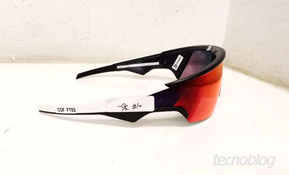 Imagem mostra um óculos Oakley Meta Vanguard sobre uma mesa branca. Na parte inferior direita, o logotipo do "tecnoblog".