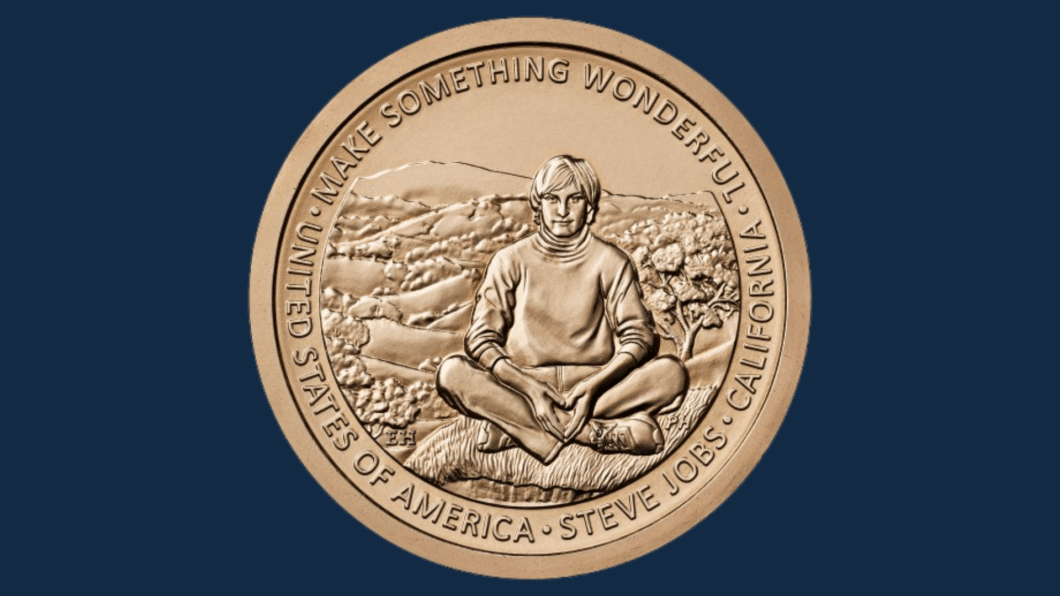 Imagem mostra uma moeda com o desenho de Steve Jobs sentado. O fundo da imagem é azul
