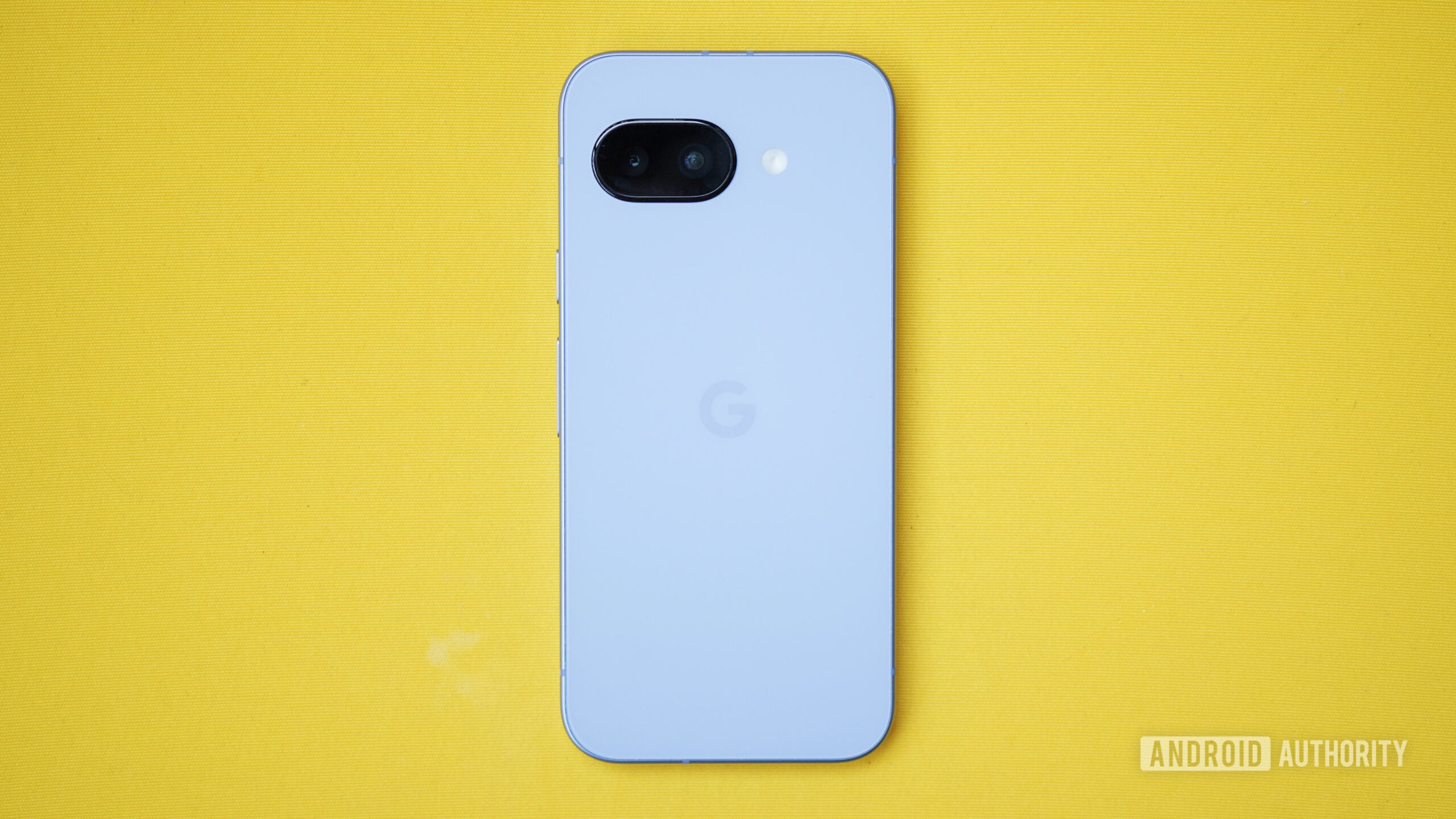 O Google Pixel 9a virado para baixo em uma almofada amarela.