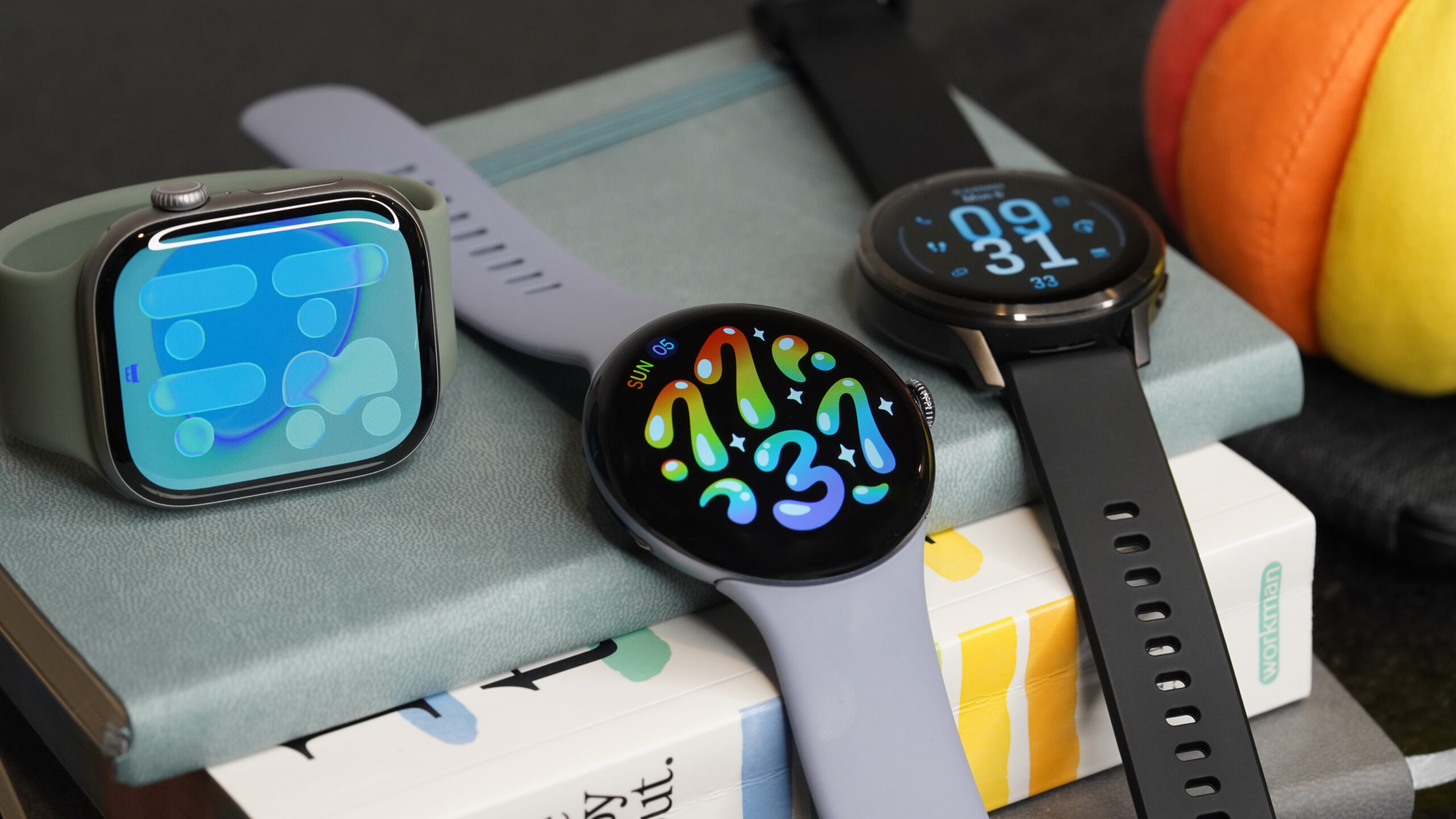 Pixel Watch 4 alternativas Um Pixel Watch 4 repousa sobre uma pilha de livros com alternativas de smartwatch.