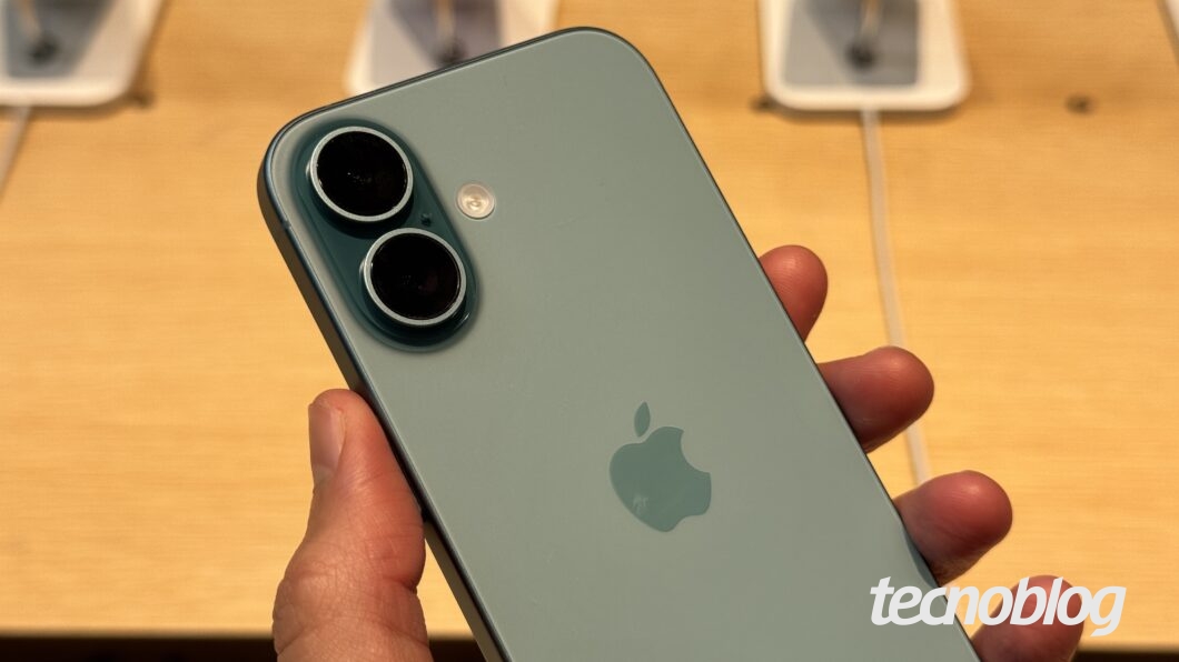 M&atilde;o segurando iPhone 16 com as duas c&acirc;meras traseiras em foco