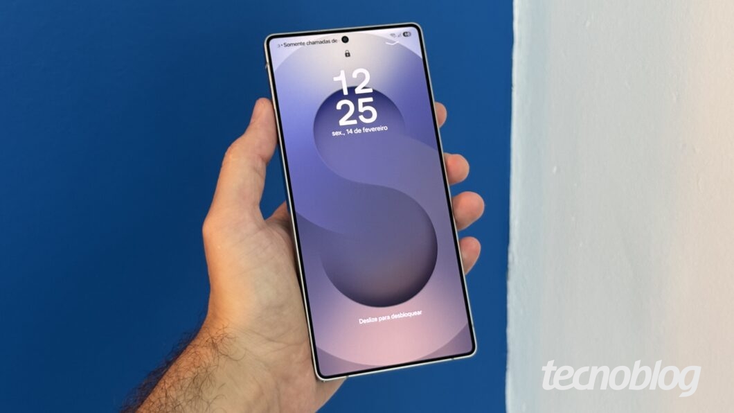 M&atilde;o segurando Galaxy S25 Ultra com tela bloqueada.