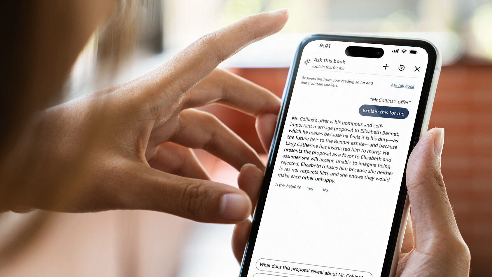 Imagem mostra uma pessoa segurando um iPhone com o app Kindle aberto, em um chat que responde quest&otilde;es sobre um livro