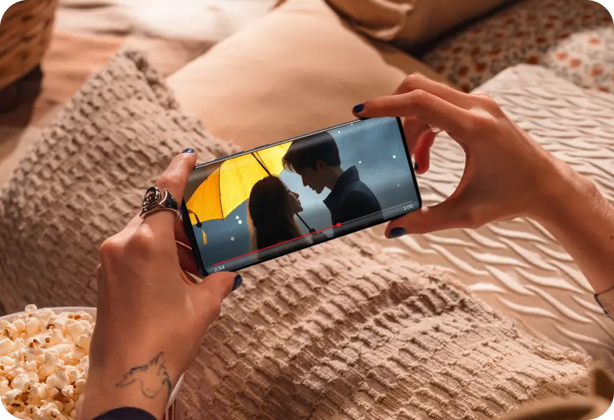 Pessoa segurando um smartphone Motorola Edge 60 Fusion enquanto assiste a um filme rom&acirc;ntico.
