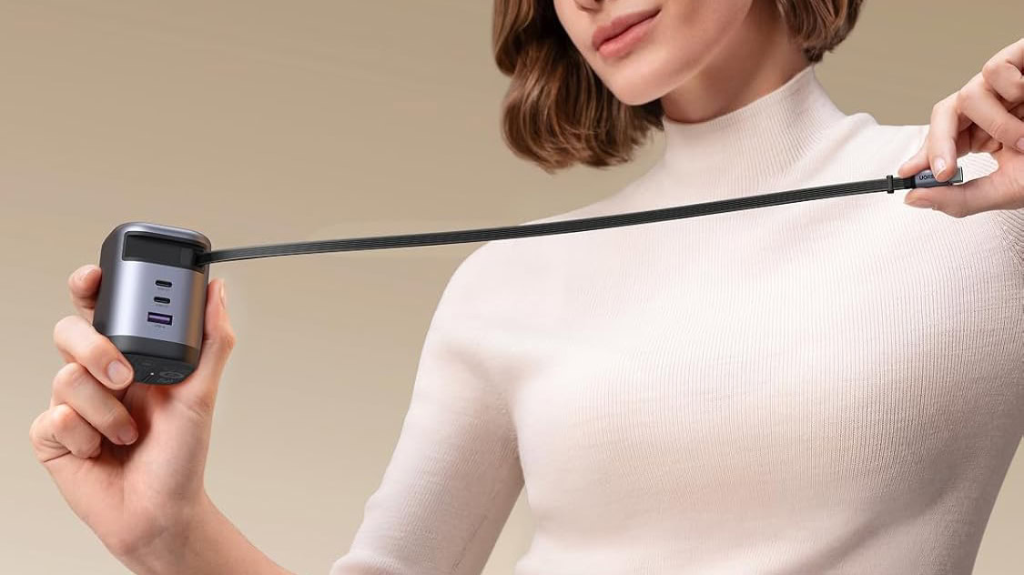 Mulher segurando carregador UGREEN 100W 4 em 1 GaN USB C com cabo retr&aacute;til