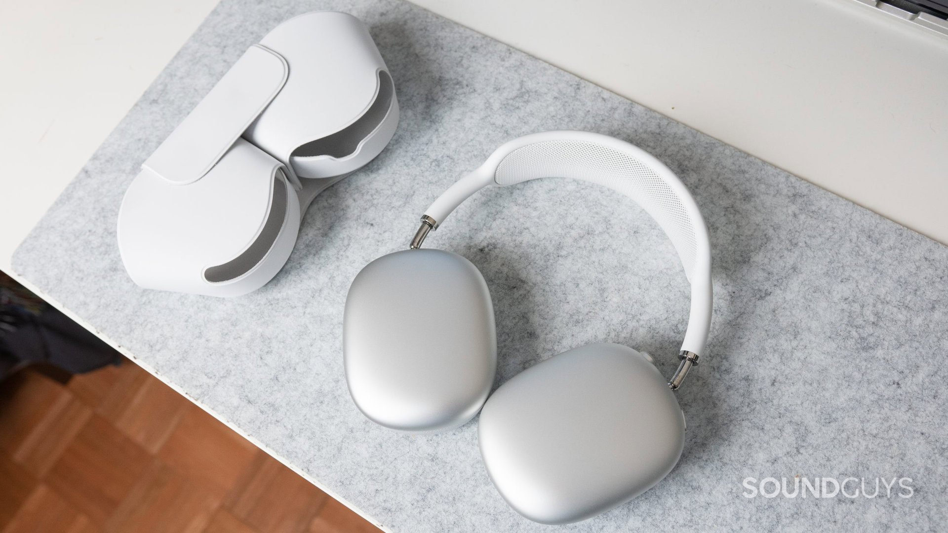 O Apple AirPods Max e seu case inteligente em uma mesa branca.