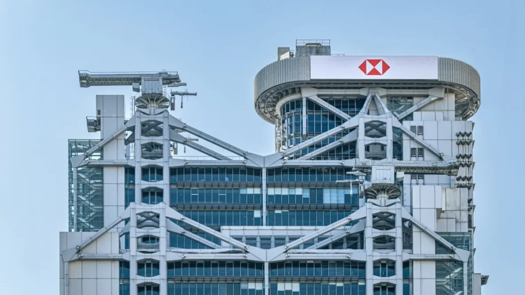 Foto do topo do pr&eacute;dio do HSBC em Hong Kong, com um c&eacute;u azul limpo ao fundo.