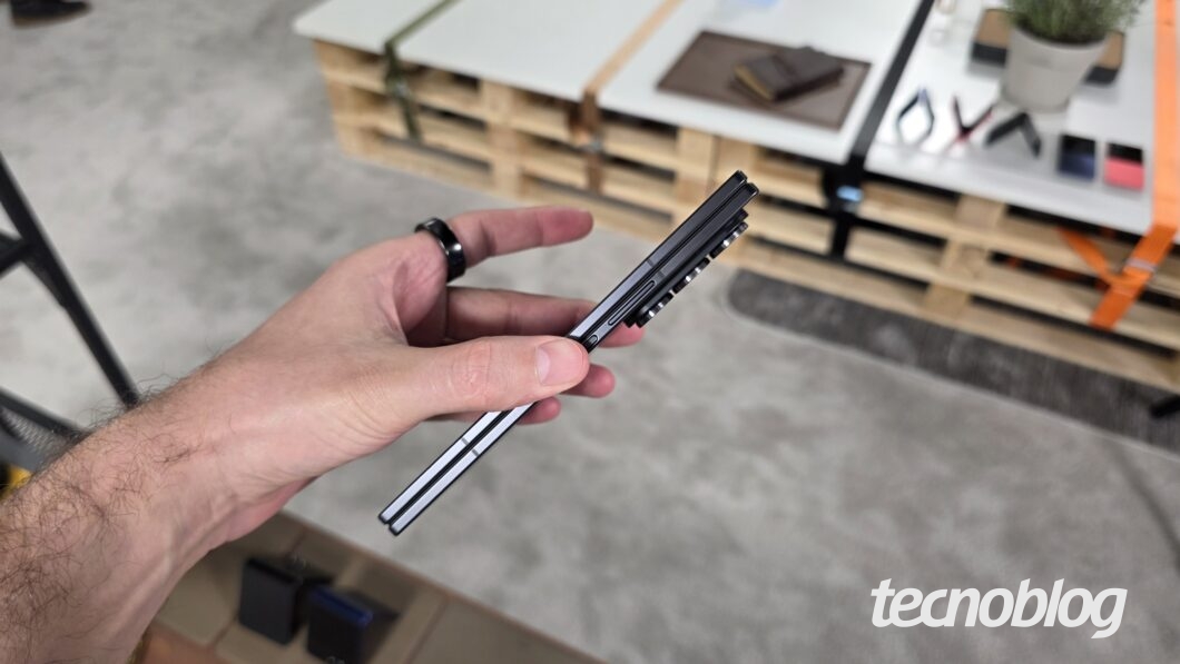 M&atilde;o segurando smartphone dobr&aacute;vel fechado, visto pela lateral