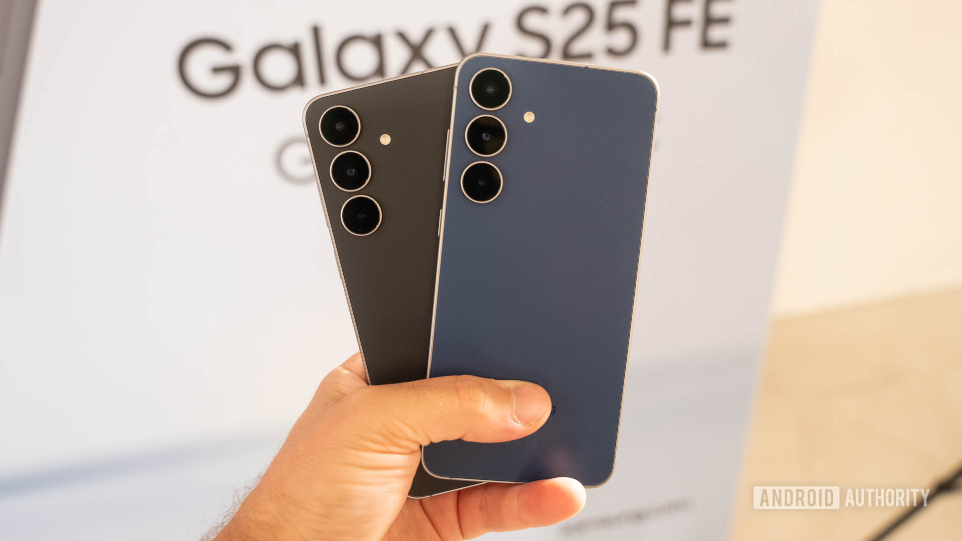 Samsung Galaxy S25 FE em Jetblack e Navy unidos na m&atilde;o de um homem