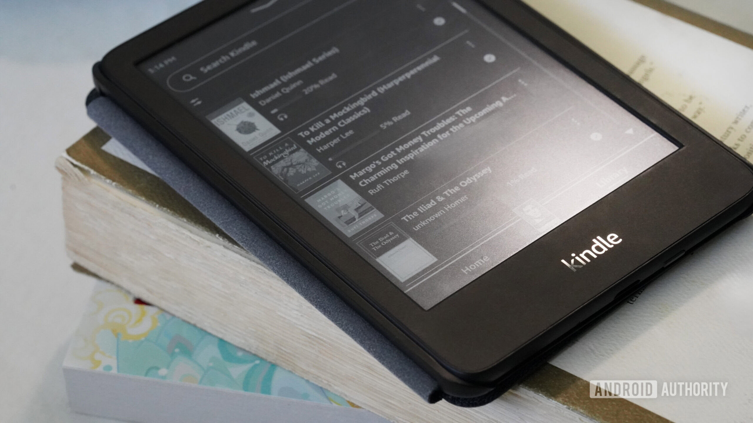 Um Kindle repousa sobre uma pequena pilha de livros de bolso.