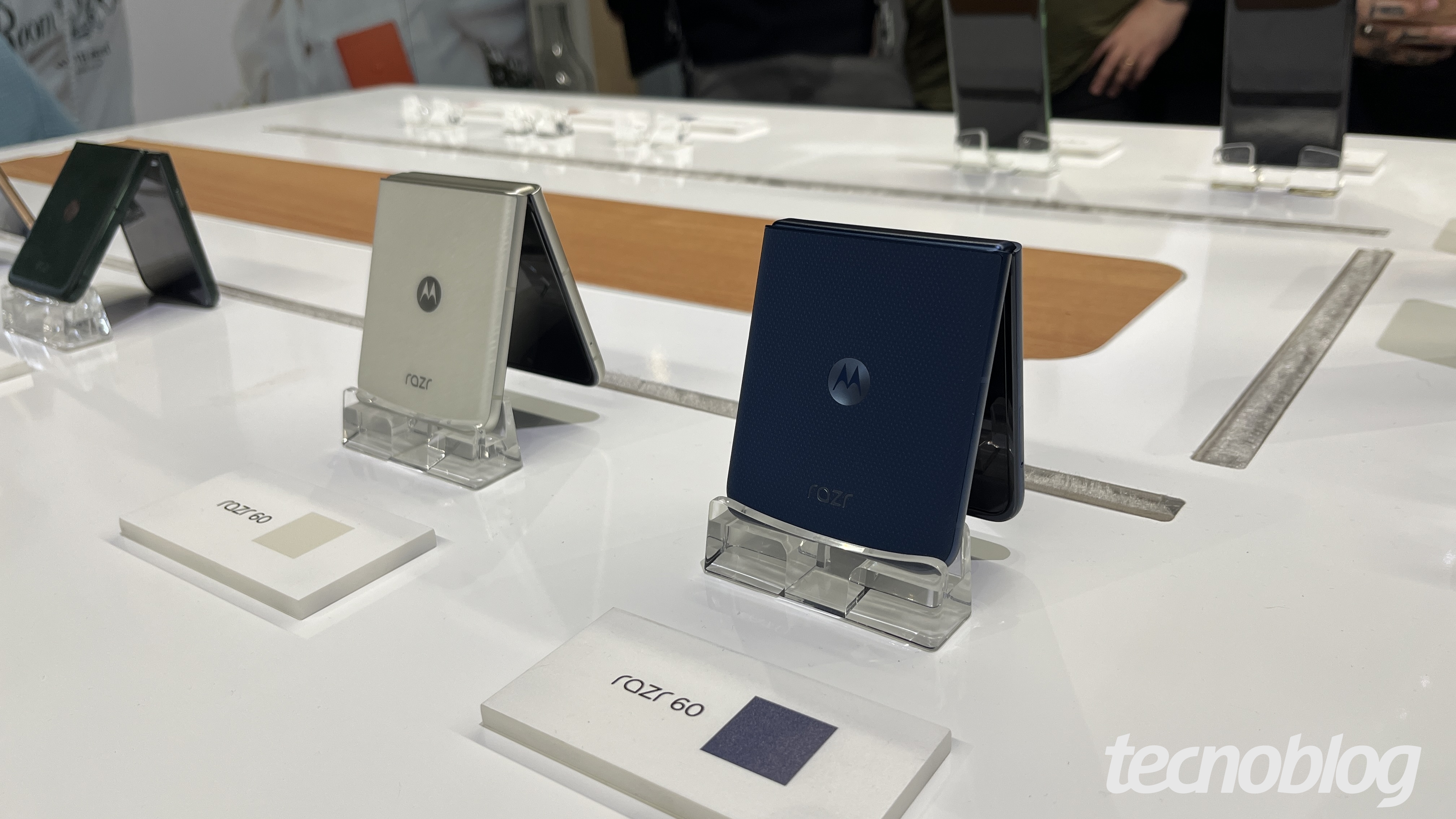 Dois smartphones dobr&aacute;veis Razr 60 lado a lado, abertos no formato tenda, apoiados sobre uma mesa. Um &eacute; cinza, outro &eacute; azul.