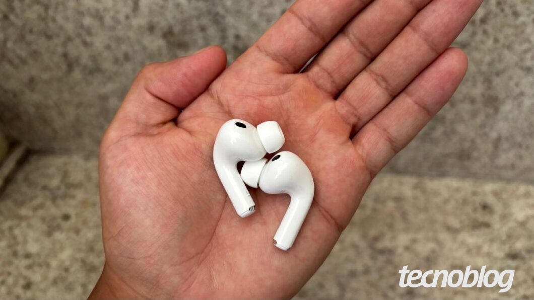 Uma m&atilde;o segurando os dois fones AirPods Pro 3 fora do estojo
