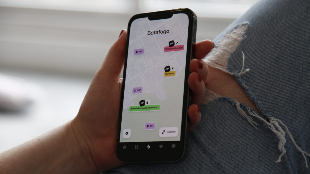 Uma m&atilde;o segura um celular com aplicativo happn exibindo o recurso Spots