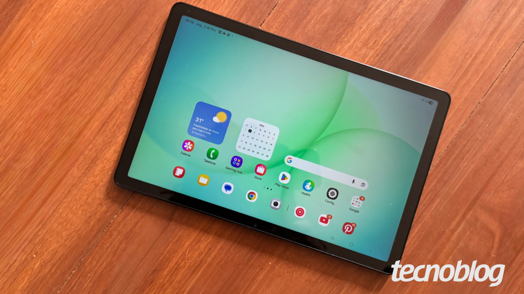 Galaxy Tab A11 Plus com tela acesa exibindo &iacute;cones de aplicativos sobre mesa de madeira