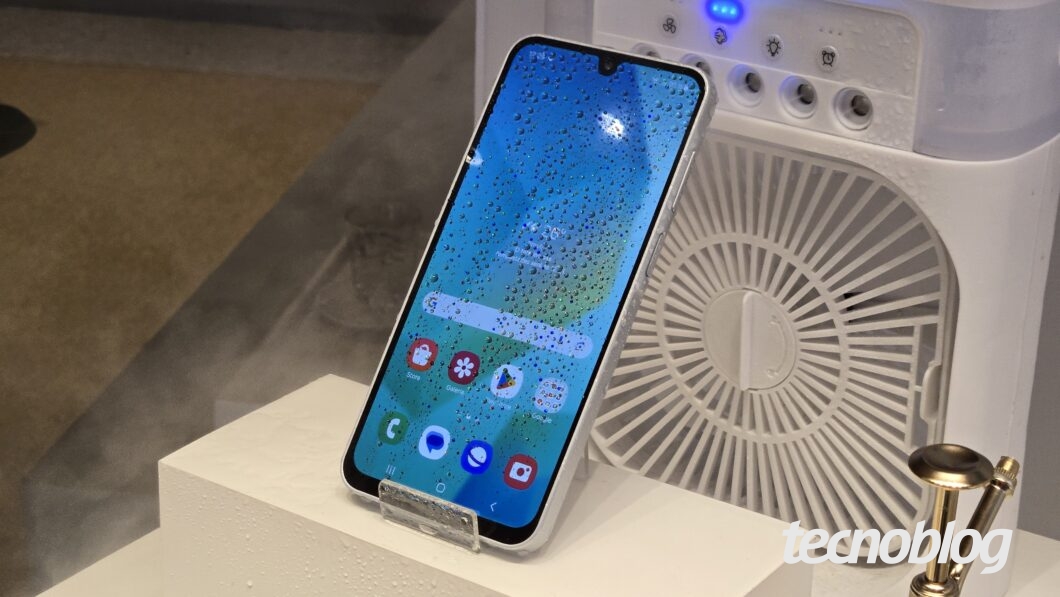 Smartphone com respingos de &aacute;gua na frente de um climatizador de ar