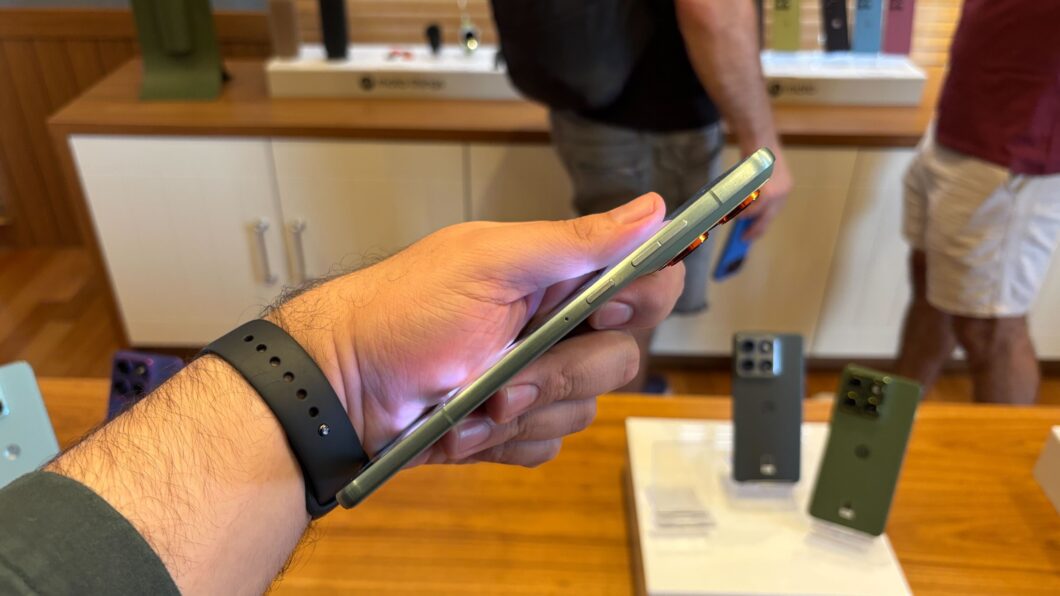 Motorola Edge 70 sendo visto lateralmente e segurado por uma m&atilde;o com um rel&oacute;gio no pulso