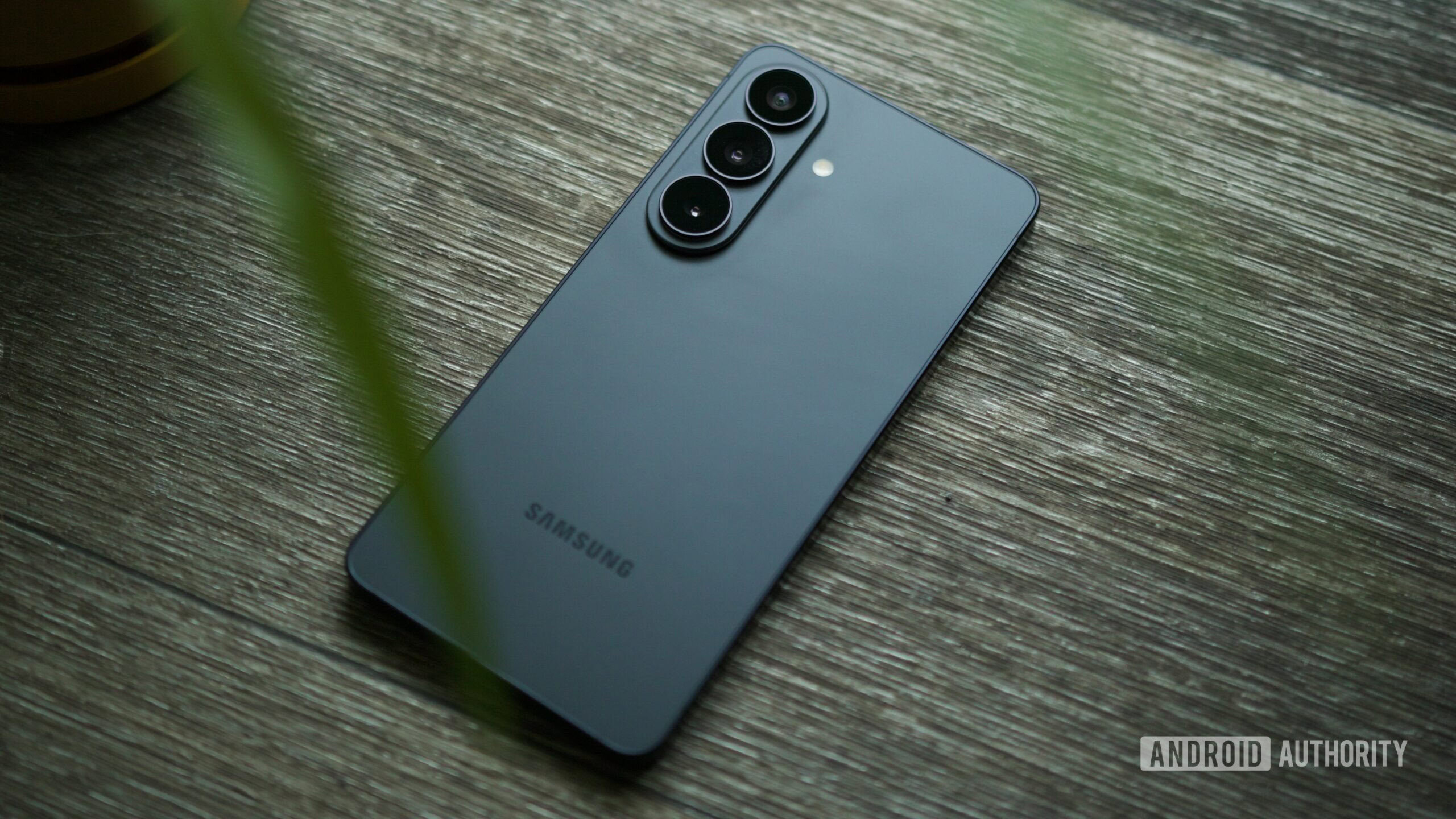 O Samsung Galaxy S26 apoiado em um piso de madeira.