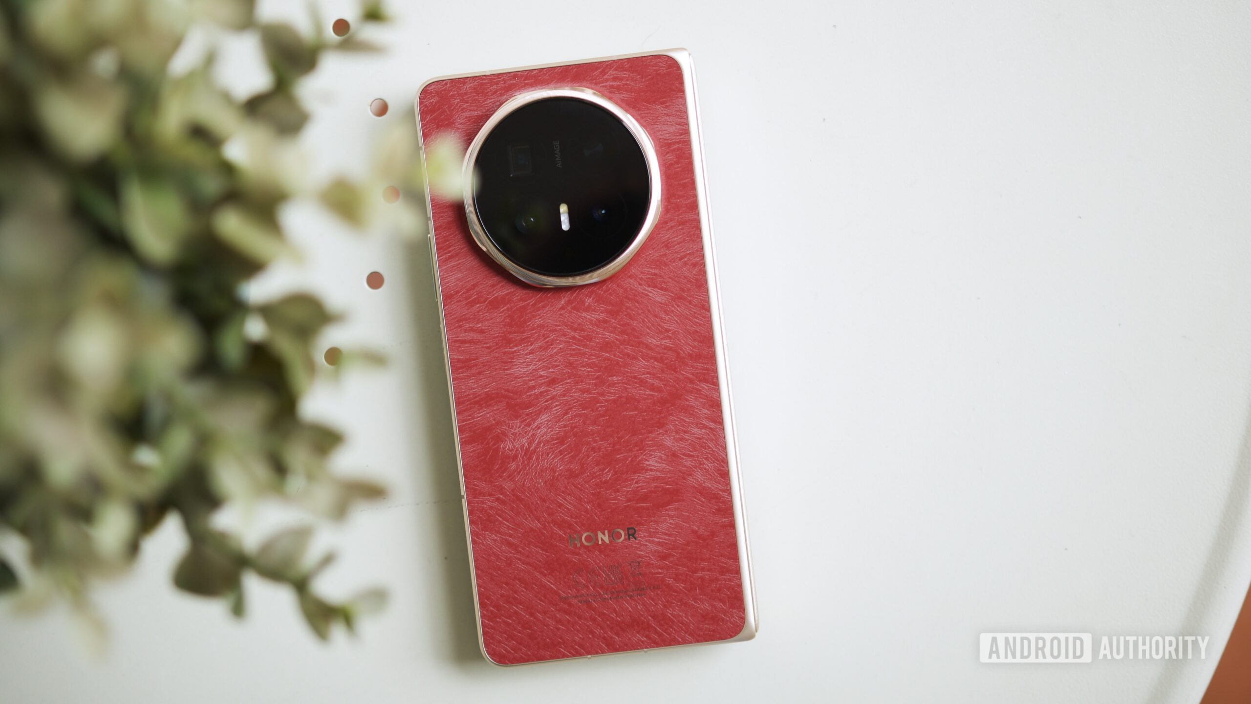 A parte de tr&aacute;s do HONOR Magic V6 vermelho sobre uma mesa.