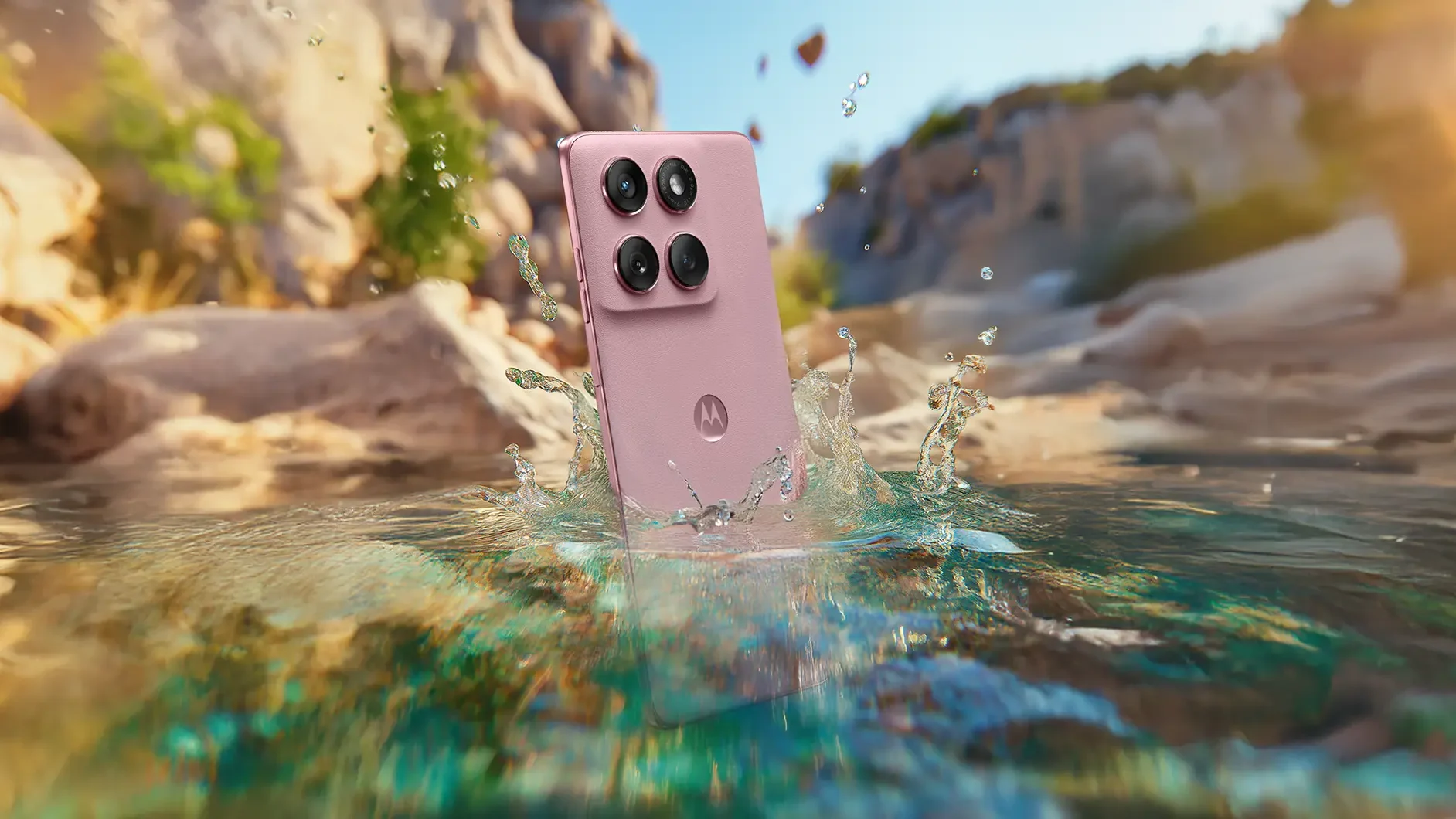 Smartphone Motorola Edge 60 Fusion na cor rosa caindo na &aacute;gua, destacando sua resist&ecirc;ncia &agrave; &aacute;gua, com um cen&aacute;rio de pedras e natureza ao fundo.