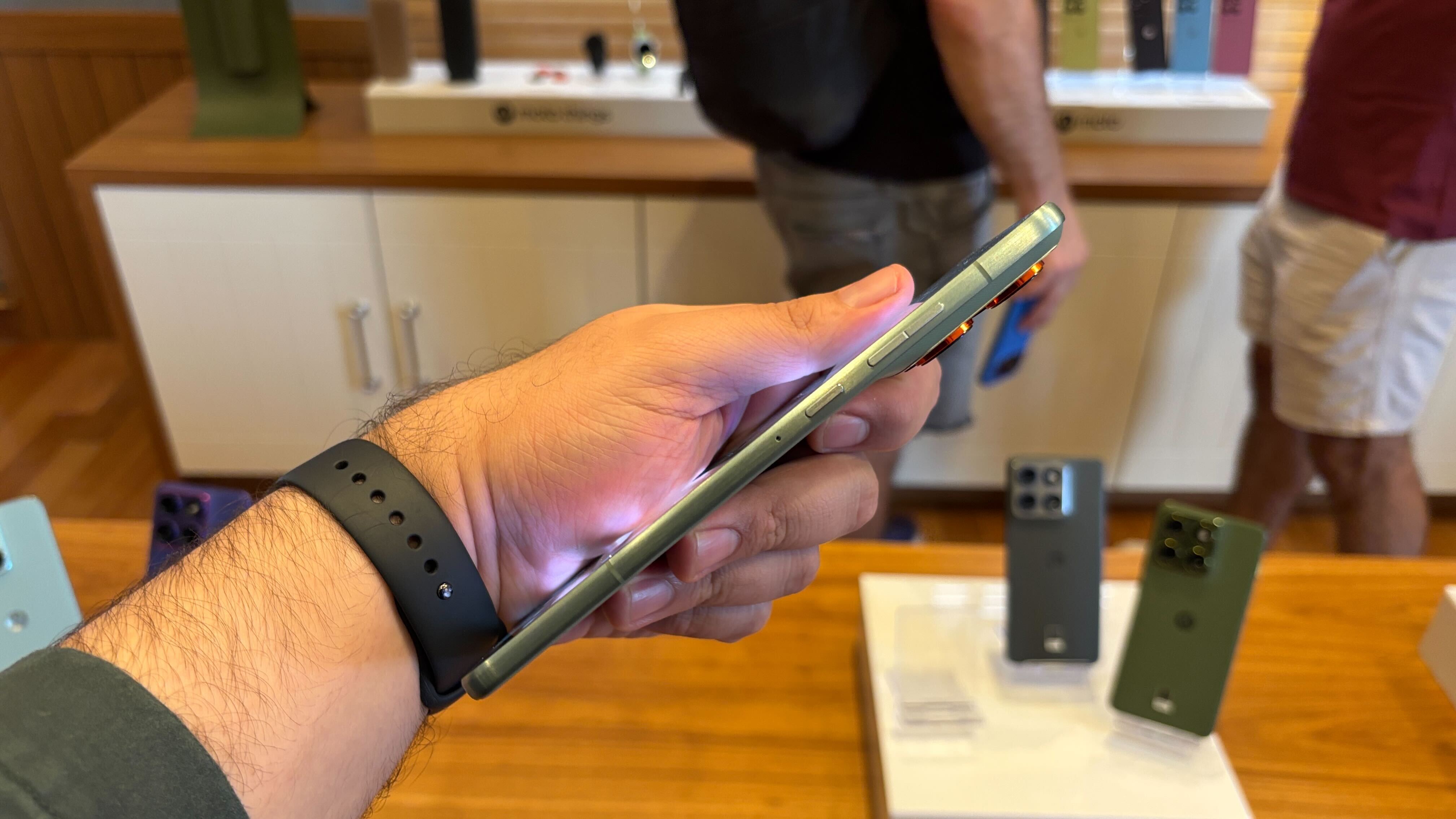 Motorola Edge 70 sendo visto lateralmente e segurado por uma m&atilde;o com um rel&oacute;gio no pulso