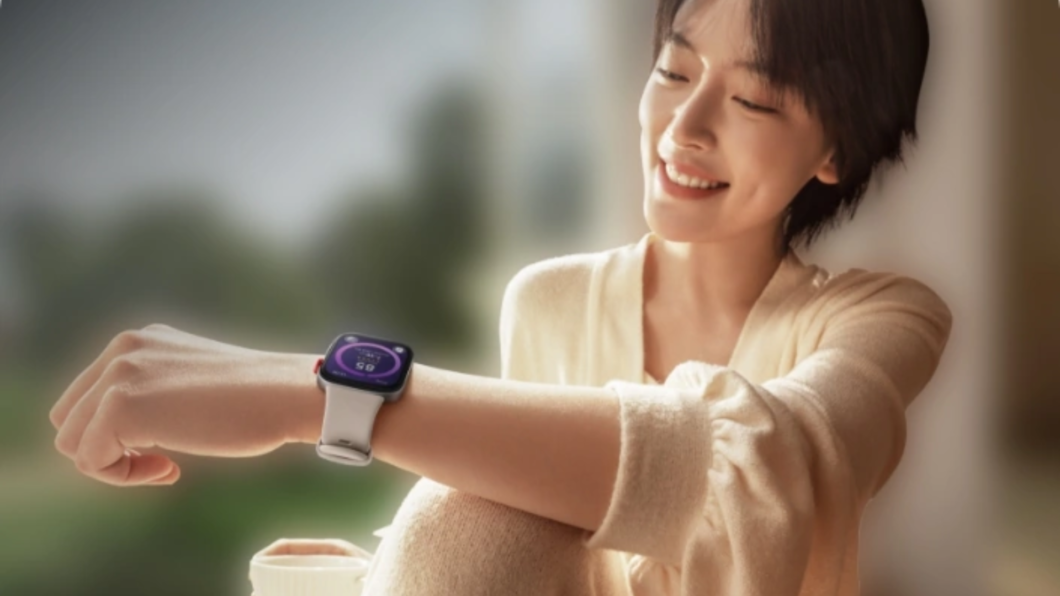 Mulher segurando um copo e olhando a tela do Huawei Watch Fit 3  amarrado no pulso