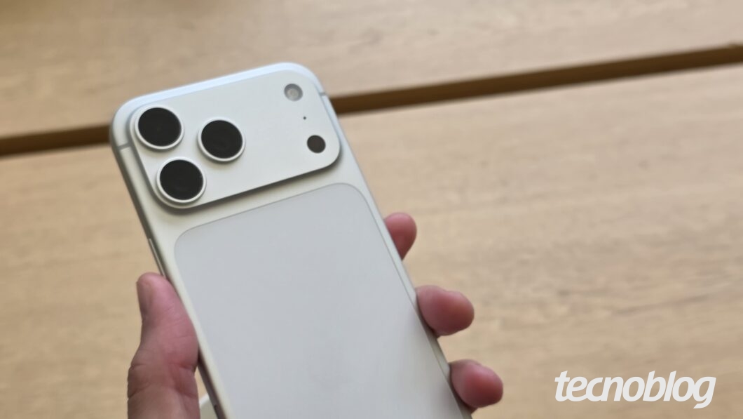 M&atilde;o segurando iPhone 17 Pro Max prateado com as c&acirc;meras traseiras em destaque