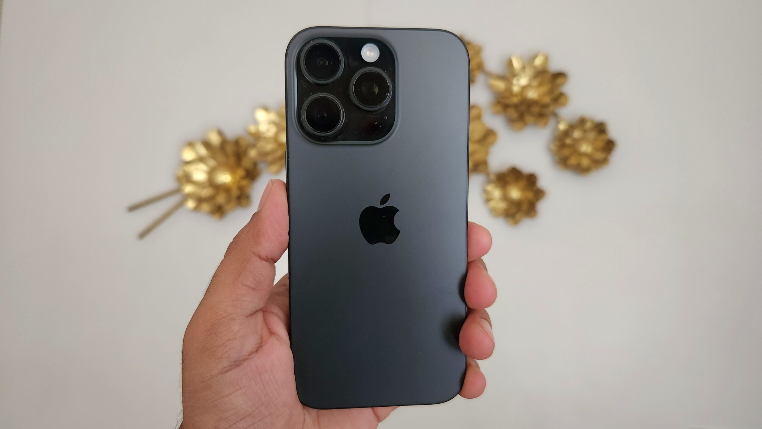 Uma m&atilde;o segurando um iPhone 16 Pro preto