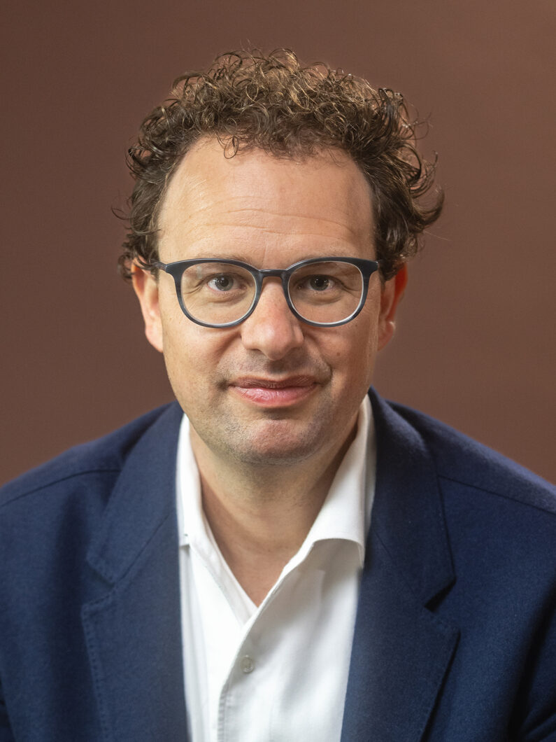 Foto de Dario Amodei, de camisa branca e terno azul.