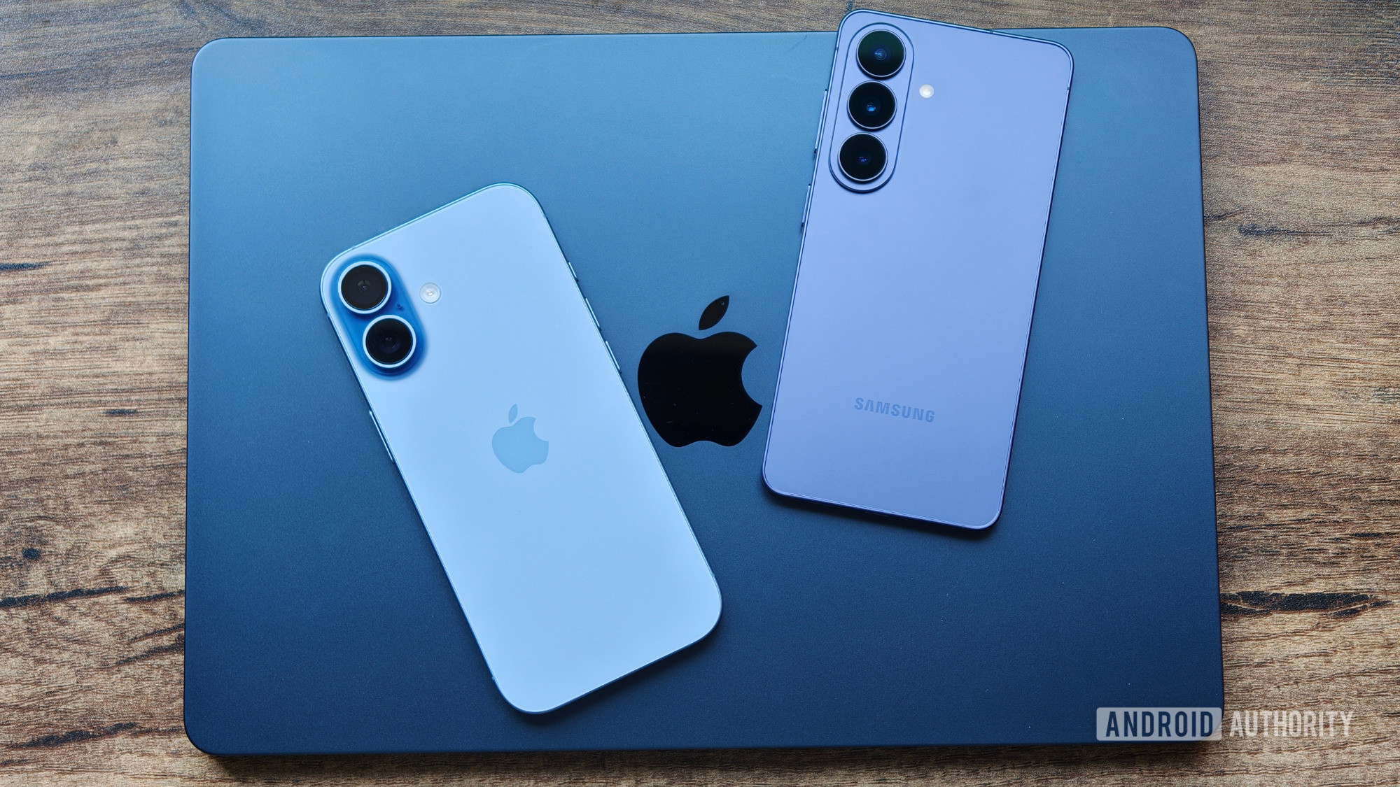 MacBook na mesa com iPhone 17 e Galaxy S26 em cima MacBook na mesa com iPhone 17 e Galaxy S26 em cima