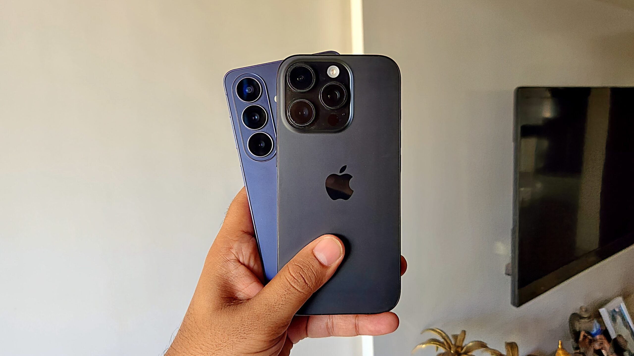 Uma m&atilde;o segurando o S26 e o ​​iPhone 16 Pro