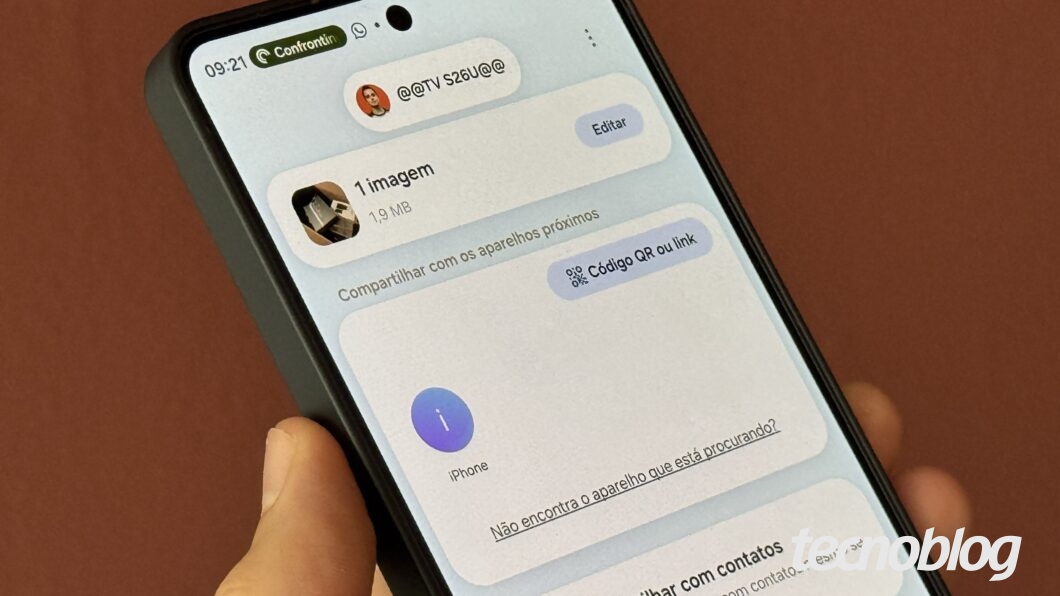 Mão segurando celular, com ferramenta de compartilhamento na tela