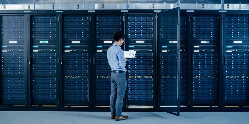 Técnico observa servidores de mainframe em um data center, mostrando a importância de mão de obra qualificada