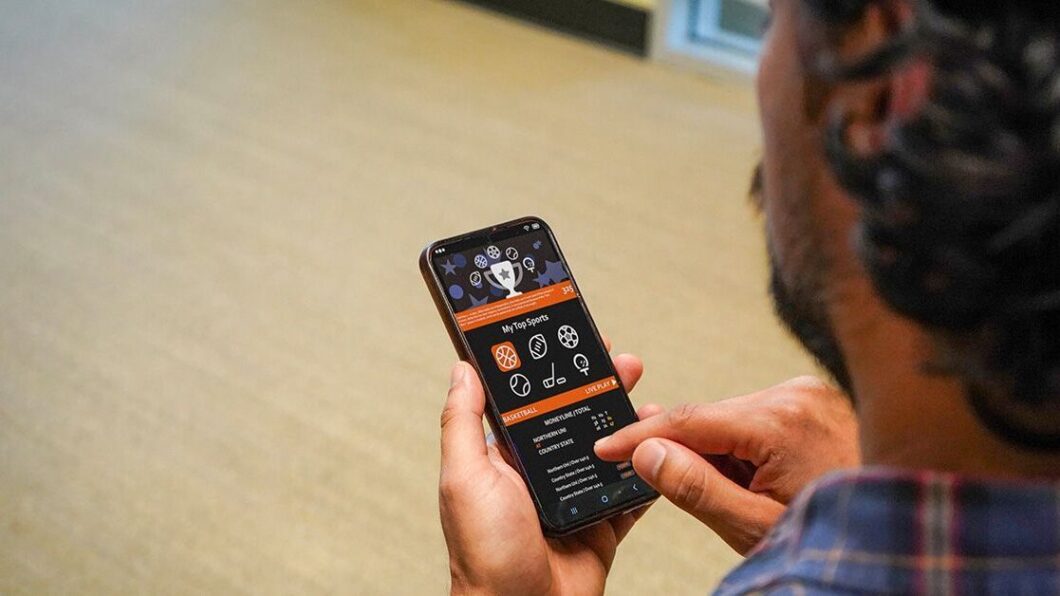 Foto de smartphone na mão de homem usando um aplicativo de apostas (bets)