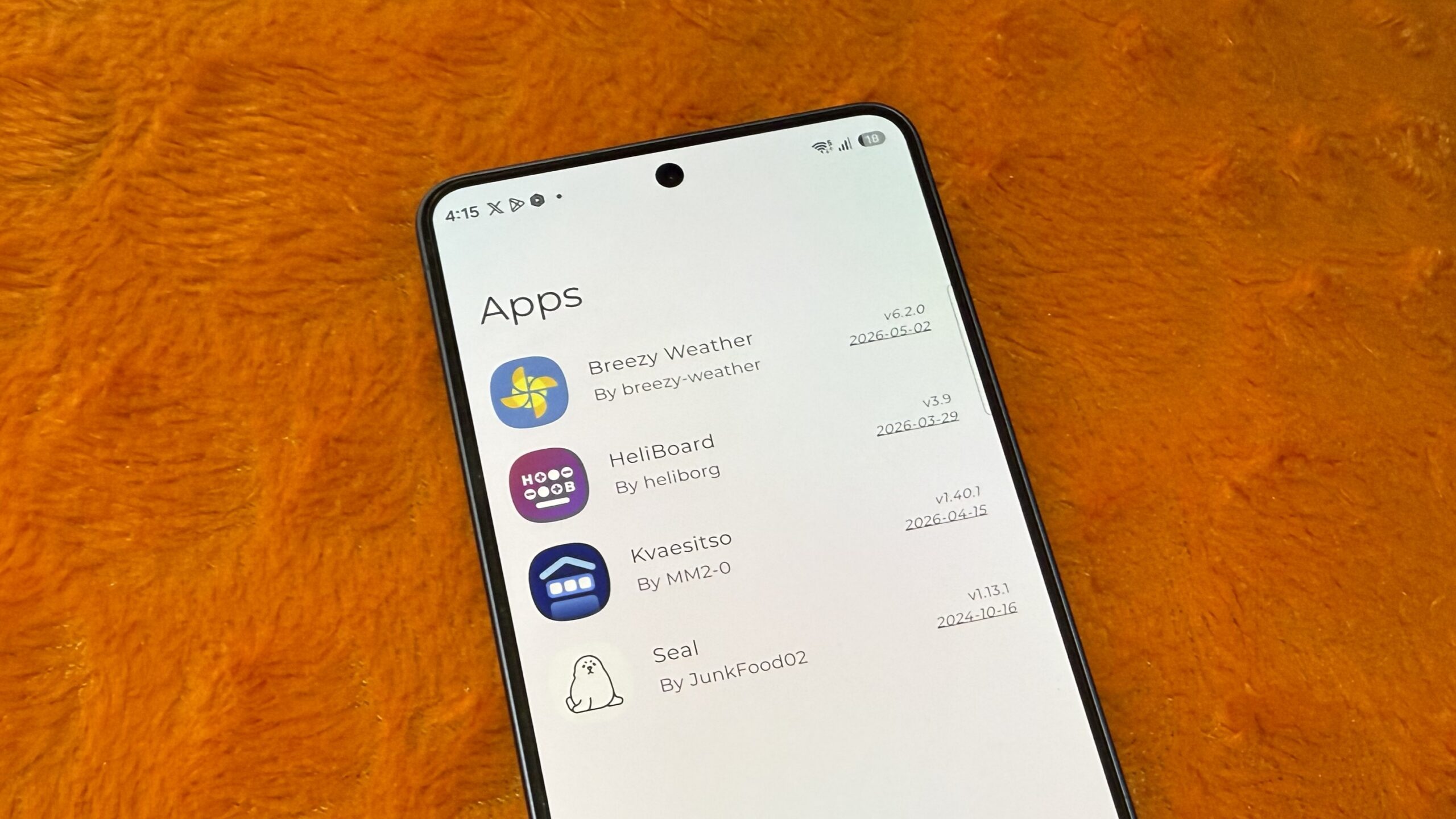 Telefone Galaxy em uma almofada laranja mostrando uma lista de aplicativos